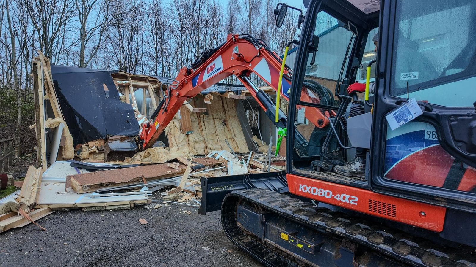 Excavator demolishing a porta cabin